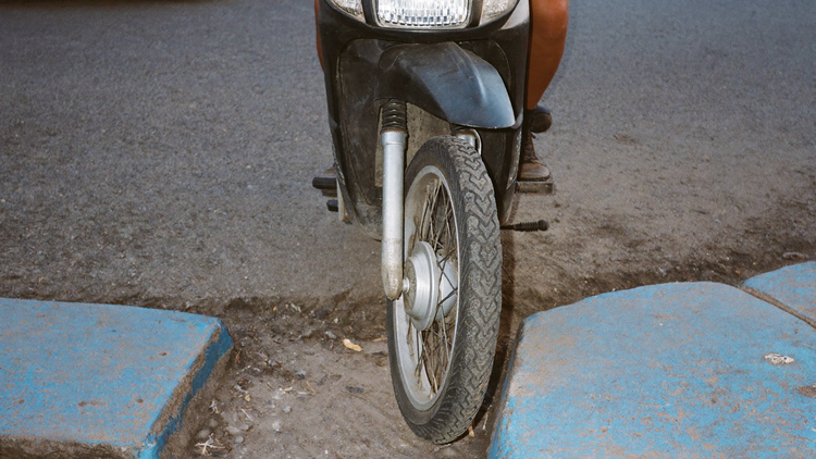 Rueda delantera de un scooter estacionado en una calle de Lima