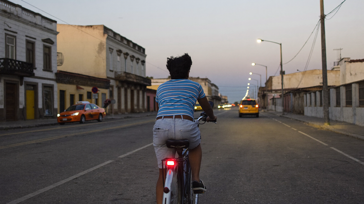 Ciclista en una calle de Lima al anochecer, con una luz roja pequeña en el tubo del asiento